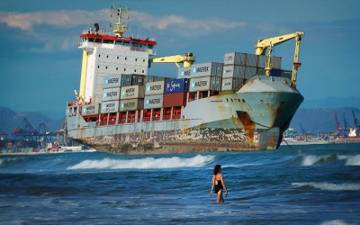 FREIGHTENED_Swimmers share the beach with a rusty container ship